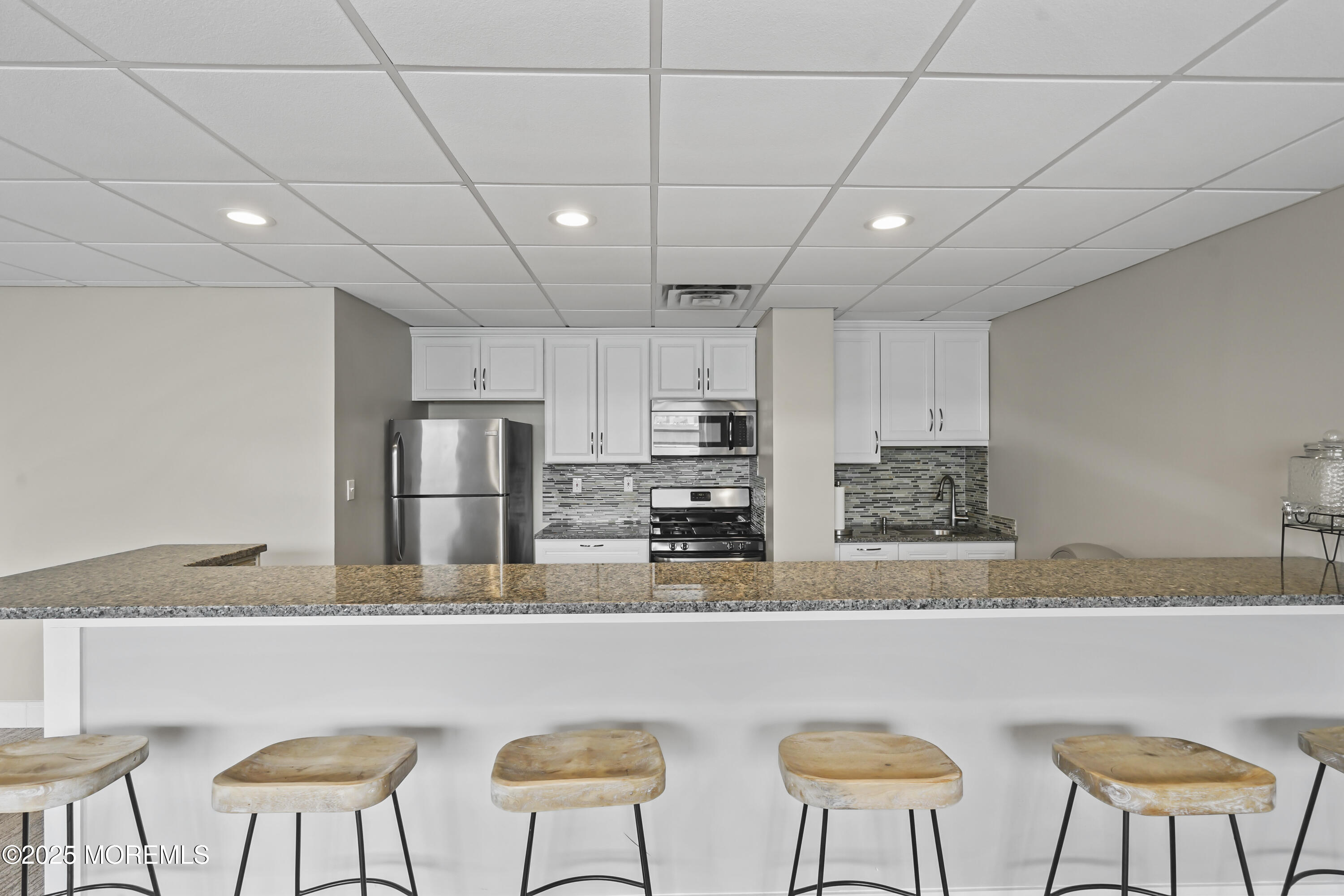675 Ocean Avenue, Unit 9F Long Branch, NJ 07740 - Photo 27 of 31 a kitchen with stainless steel appliances granite countertop a table chairs and a refrigerator