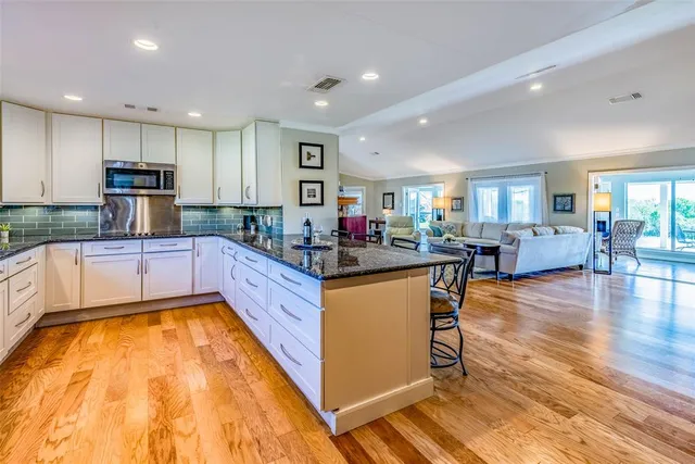 a kitchen with stainless steel appliances granite countertop a stove a refrigerator a sink a dining table and chairs