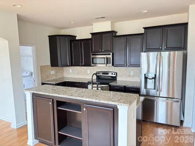 a kitchen with kitchen island granite countertop stainless steel appliances and wooden cabinets
