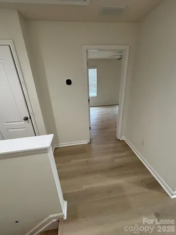 a view of a hallway with wooden floor and staircase