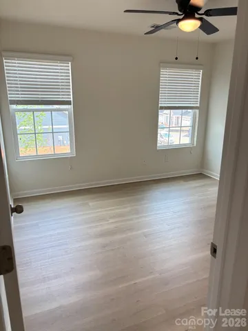 an empty room with wooden floor and fan