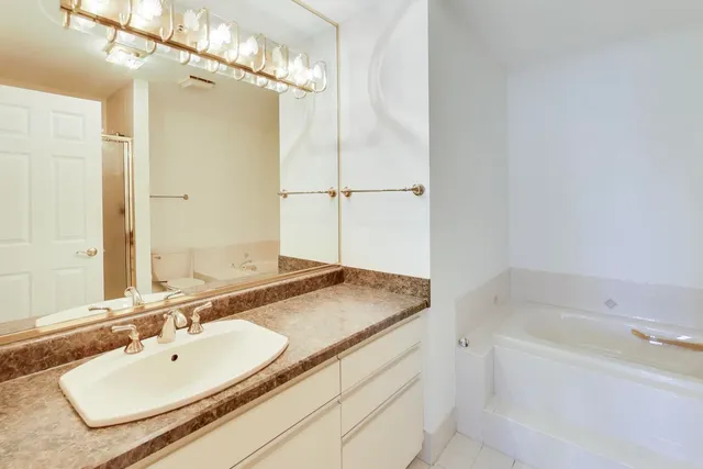 a bathroom with a tub sink and mirror