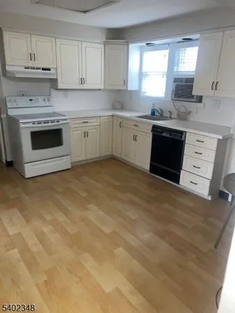 a kitchen with stainless steel appliances granite countertop a stove a sink and white cabinets