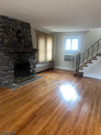 an empty room with wooden floor fireplace and windows