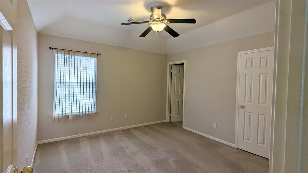 20909 Springport Court Katy, TX 77450 - Photo 25 of 39 Bright, cozy bedroom featuring a ceiling fan, neutral walls, and plush carpeting, complemented by natural light from a window with sheer curtains.