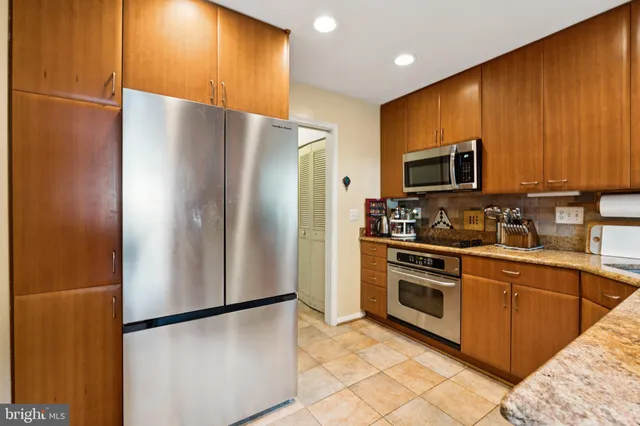 a kitchen with stainless steel appliances granite countertop a refrigerator a microwave a sink and a refrigerator