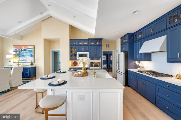 a kitchen with stainless steel appliances kitchen island granite countertop a sink a stove a refrigerator cabinets and chairs