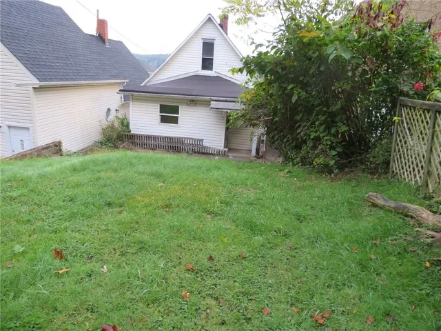 a view of a yard in front of a house with plants and large tree