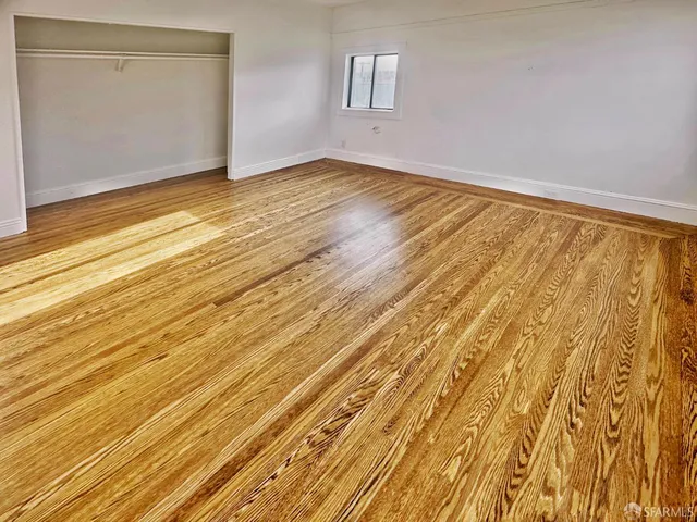 a view of empty room with wooden floor and fan