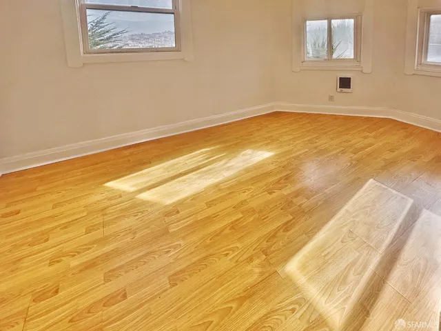 a view of empty room with wooden floor and wall painting