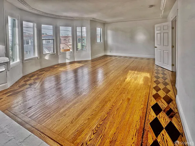 a view of an empty room with a window and wooden floor