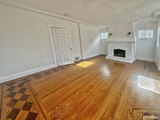 a view of empty room with wooden floor and fireplace