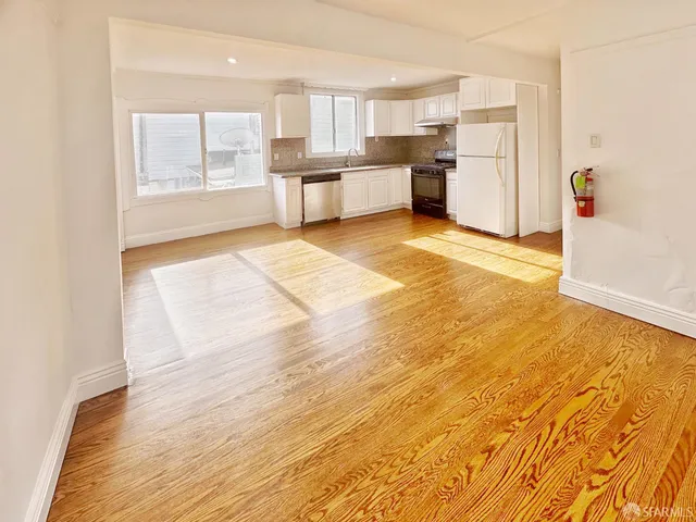 a view of a kitchen with kitchen island wooden floors stainless steel appliances