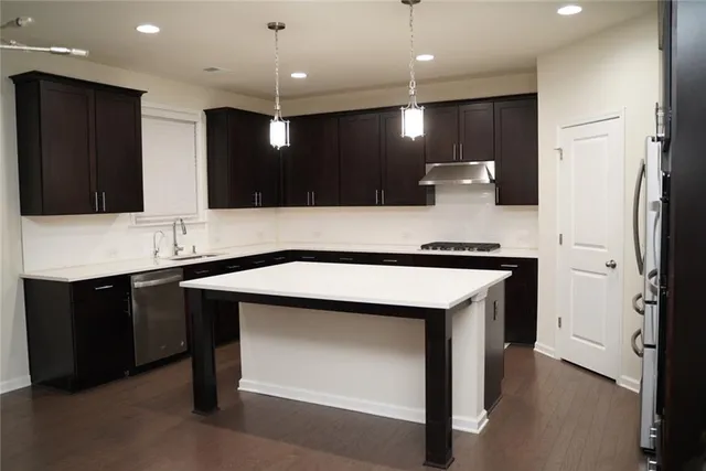 a kitchen with kitchen island a sink stainless steel appliances and cabinets