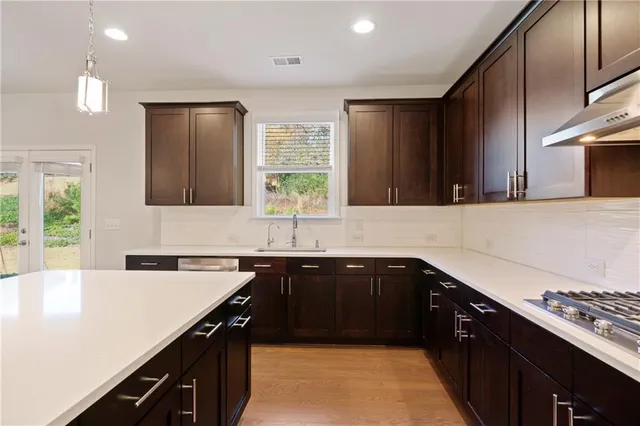 a kitchen with a sink and a stove top oven with wooden floor