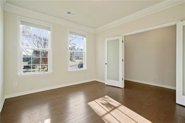 an empty room with wooden floor and windows
