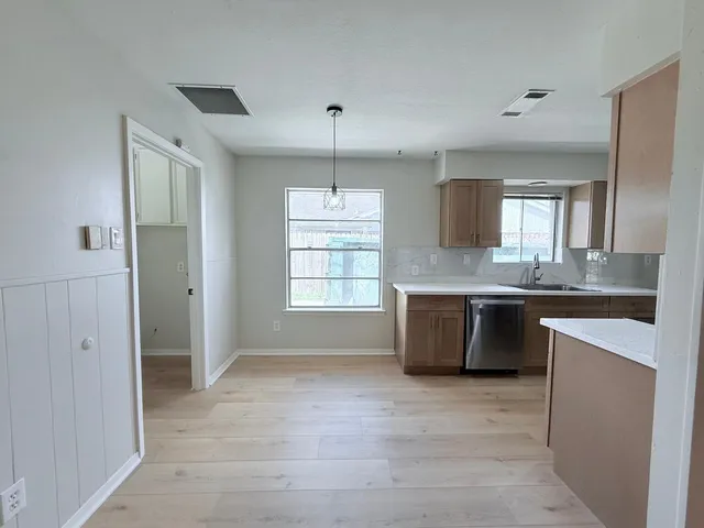 a large kitchen with granite countertop a sink and dishwasher a stove a refrigerator with wooden floors