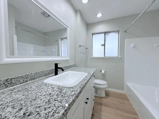 a bathroom with a granite countertop sink a toilet and a mirror
