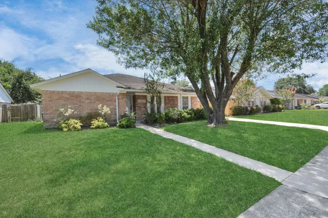 a view of a house with a big yard potted plants and large tree