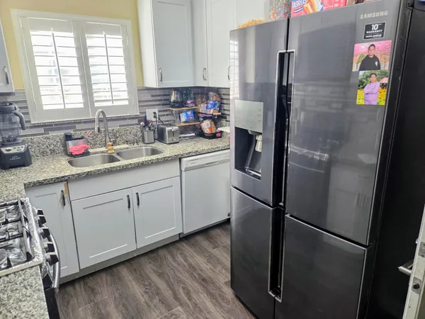 a kitchen with stainless steel appliances a refrigerator sink and wooden floor