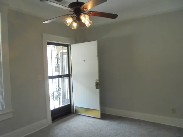 an empty room with chandelier fan and windows