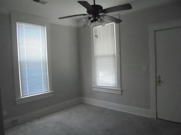 an empty room with a window and a fan