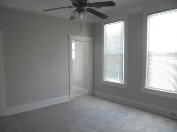 an empty room with a window and a fan