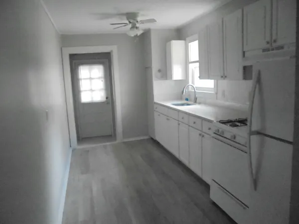 a kitchen with stainless steel appliances granite countertop a refrigerator a sink dishwasher and white cabinets with wooden floor