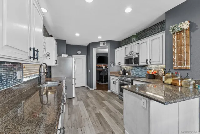 a kitchen with stainless steel appliances granite countertop a refrigerator stove microwave and sink