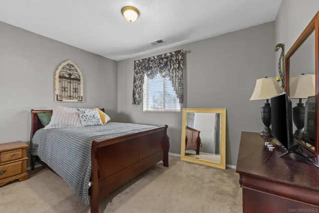 a bedroom with a bed and a flat tv screen on the dresser