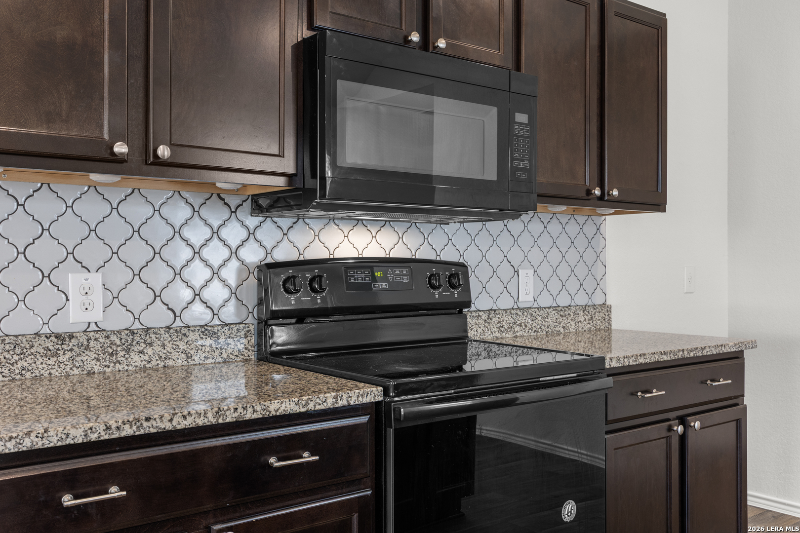 14809 Bajada Road Manor, TX 78653 - Photo 12 of 30 a kitchen with granite countertop cabinets and black appliances