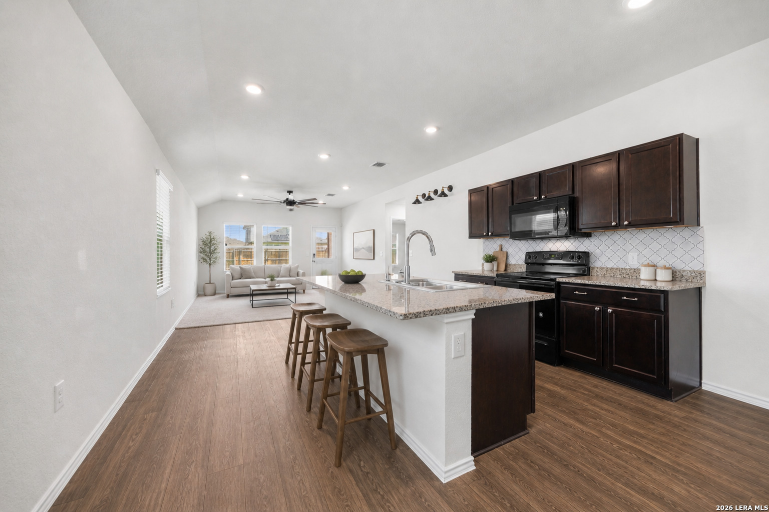 14809 Bajada Road Manor, TX 78653 - Photo 3 of 30 a kitchen with stainless steel appliances granite countertop a stove top oven a sink a refrigerator white cabinets and wooden floor