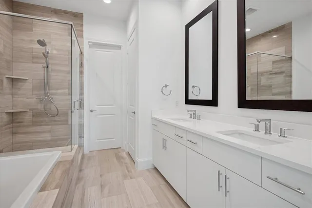 a bathroom with a double vanity sink mirror and a bathtub