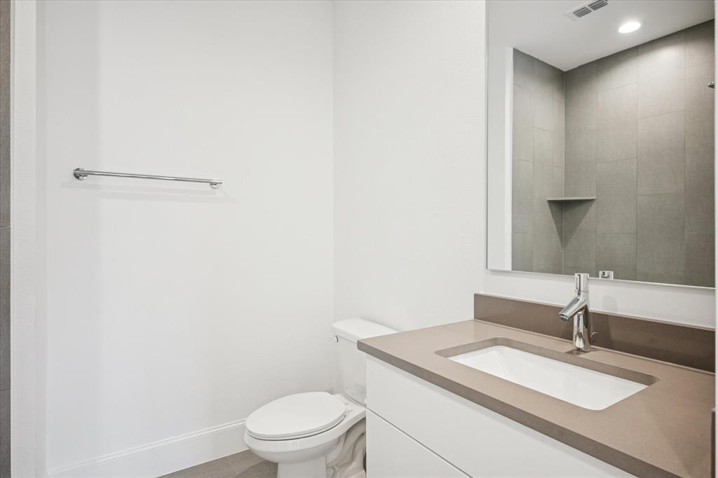 4066 Oak Circle Addison, TX 75001 - Photo 17 of 31 a bathroom with a granite countertop sink a toilet and a mirror