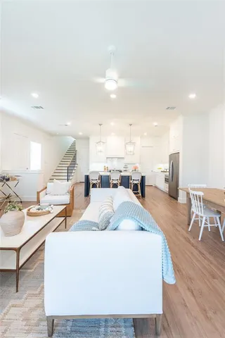 a living room with couches and kitchen view with wooden floor