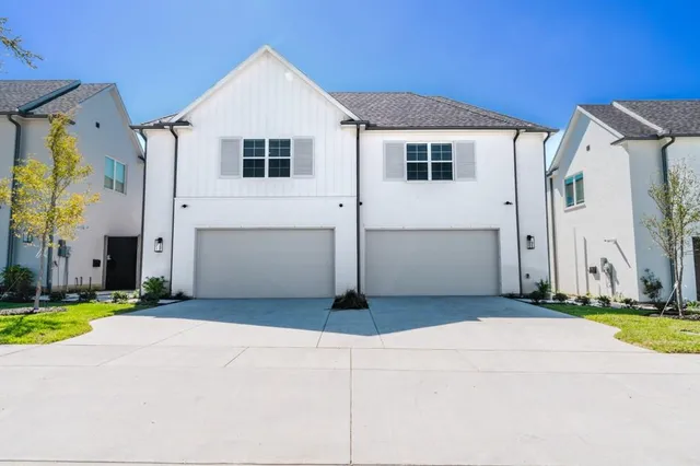 a white house that has a small yard and parking space