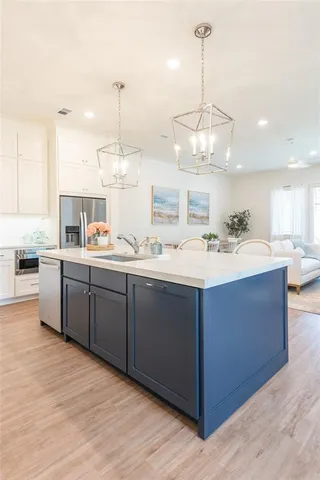 a room with kitchen island stainless steel appliances a sink and cabinets