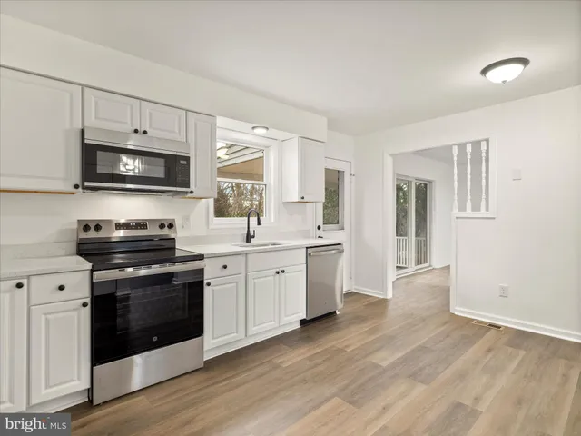 a kitchen with granite countertop a stove top oven a sink dishwasher a dining table and chairs with wooden floor