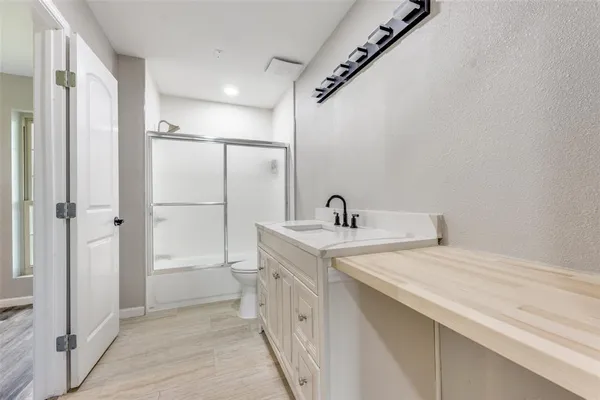 a bathroom with a granite countertop toilet a sink a mirror and vanity