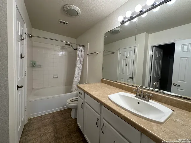 a bathroom with a granite countertop sink a toilet a mirror and shower
