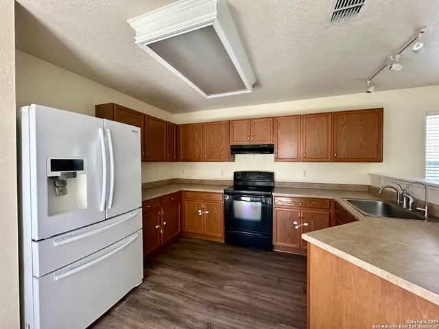 a kitchen with granite countertop a refrigerator stove and sink