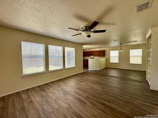a view of an empty room with a window and wooden floor