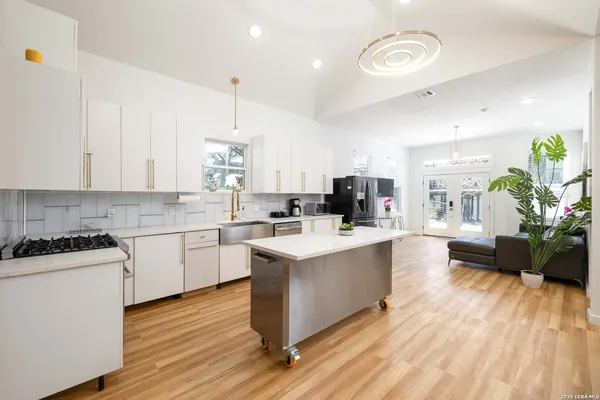 a kitchen with stove a sink and white cabinets with wooden floor