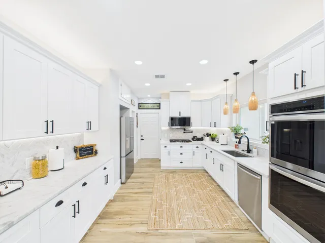 a large white kitchen with cabinets and stainless steel appliances