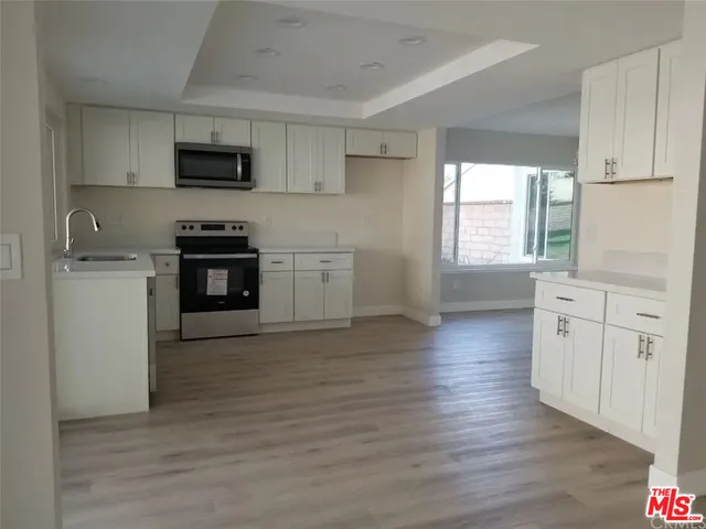 a kitchen with granite countertop a stove top oven a sink dishwasher and a refrigerator with wooden floor