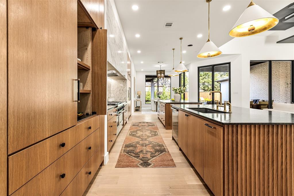 6123 Northaven Road Dallas, TX 75230 - Photo 10 of 40 Statement lighting adds dimension and warmth to the kitchen, highlighting the scale of the space while keeping it comfortable for everyday use