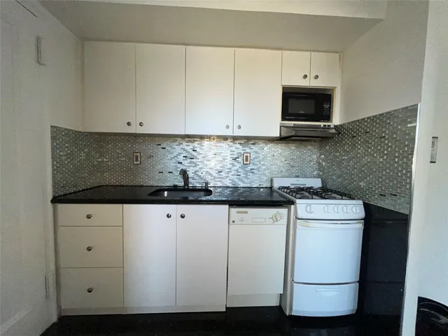 a kitchen with granite countertop white cabinets and white appliances
