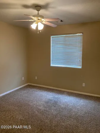 an empty room with a chandelier fan and windows