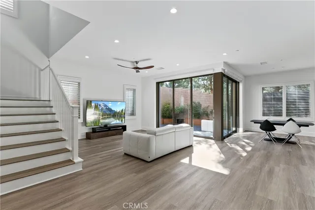 a living room with furniture large windows and wooden floor