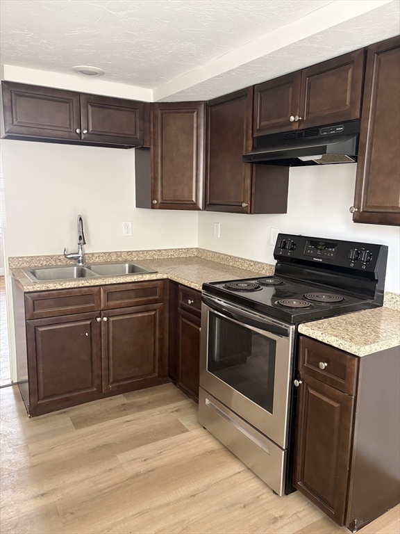7 Morrill Street, Unit 7 Nashua, NH 03064 - Photo 5 of 15 a kitchen with stainless steel appliances granite countertop a stove a sink and a microwave